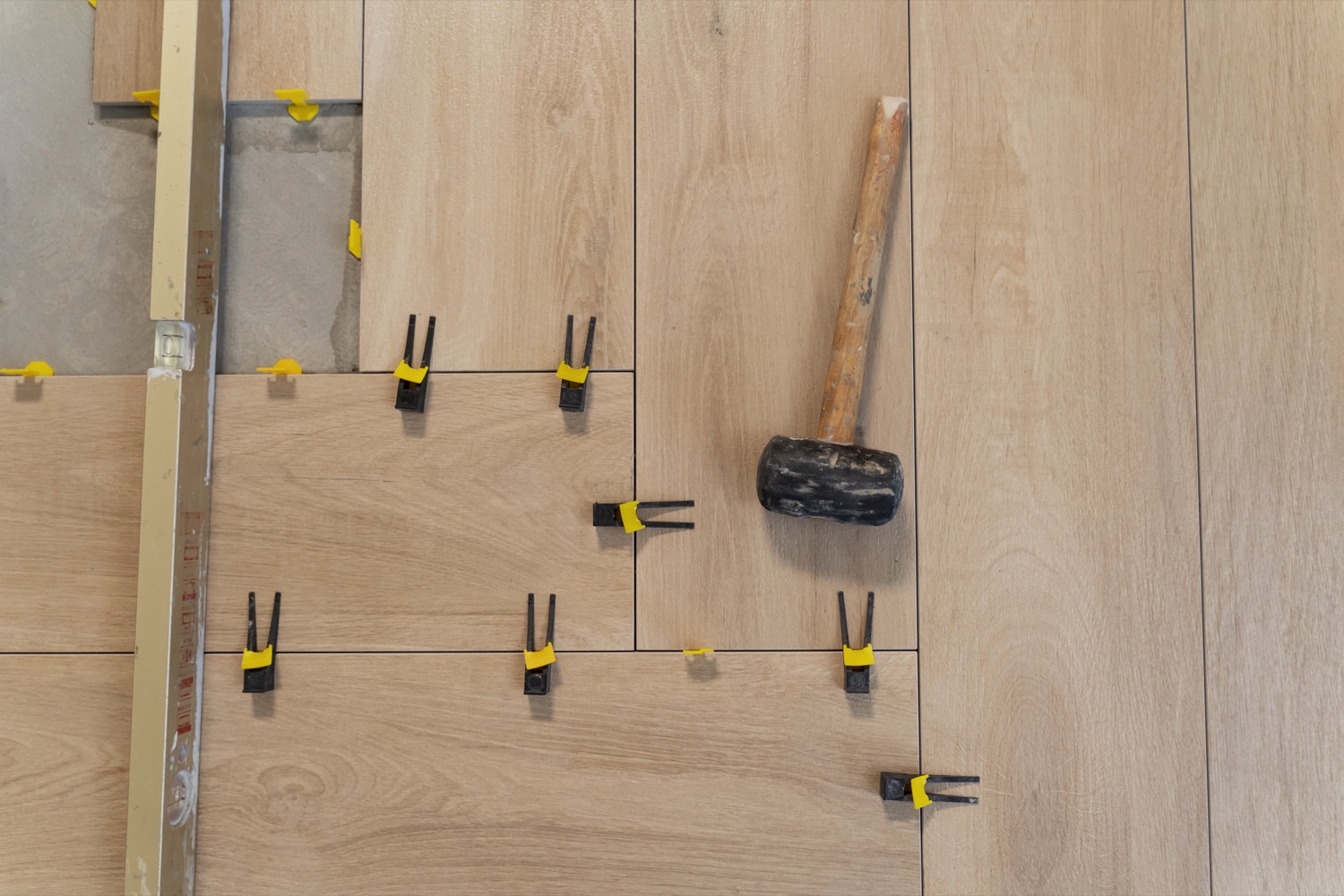Verlegen eines Laminatbodens mit Verlegehilfen und Gummihammer